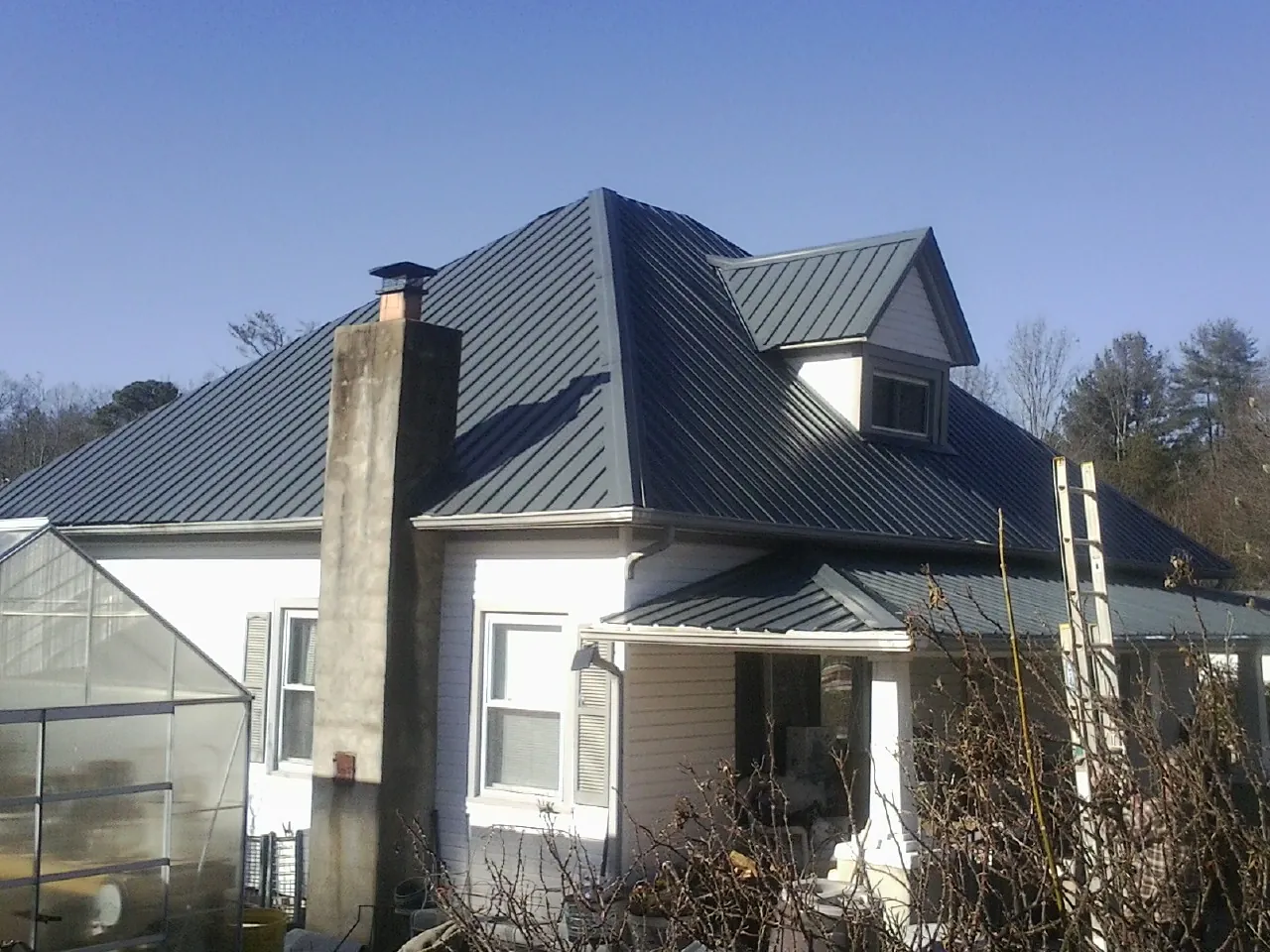Dark blue standing seam metal roof on a white farmhouse with dormer — Slate & Tile Roof Repair by Roofing Brothers in Neelyton