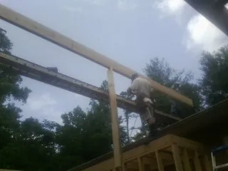 Carpenter setting a ridge beam over a new addition frame — Ice Dam Removal by Roofing Brothers in Neelyton