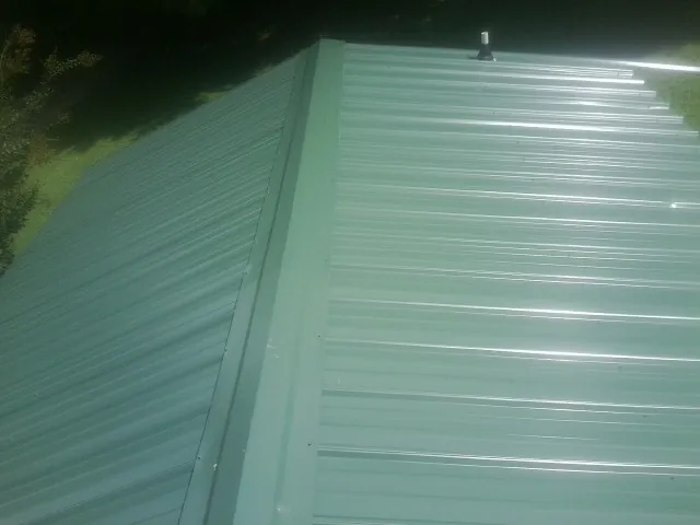 New green metal panels meeting at the ridge of a roof — Flat Roof Repair work by our crew in Neelyton