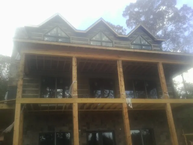 Dormers and porch framing on a large log home under construction — Roof Coating work by our crew in Neelyton