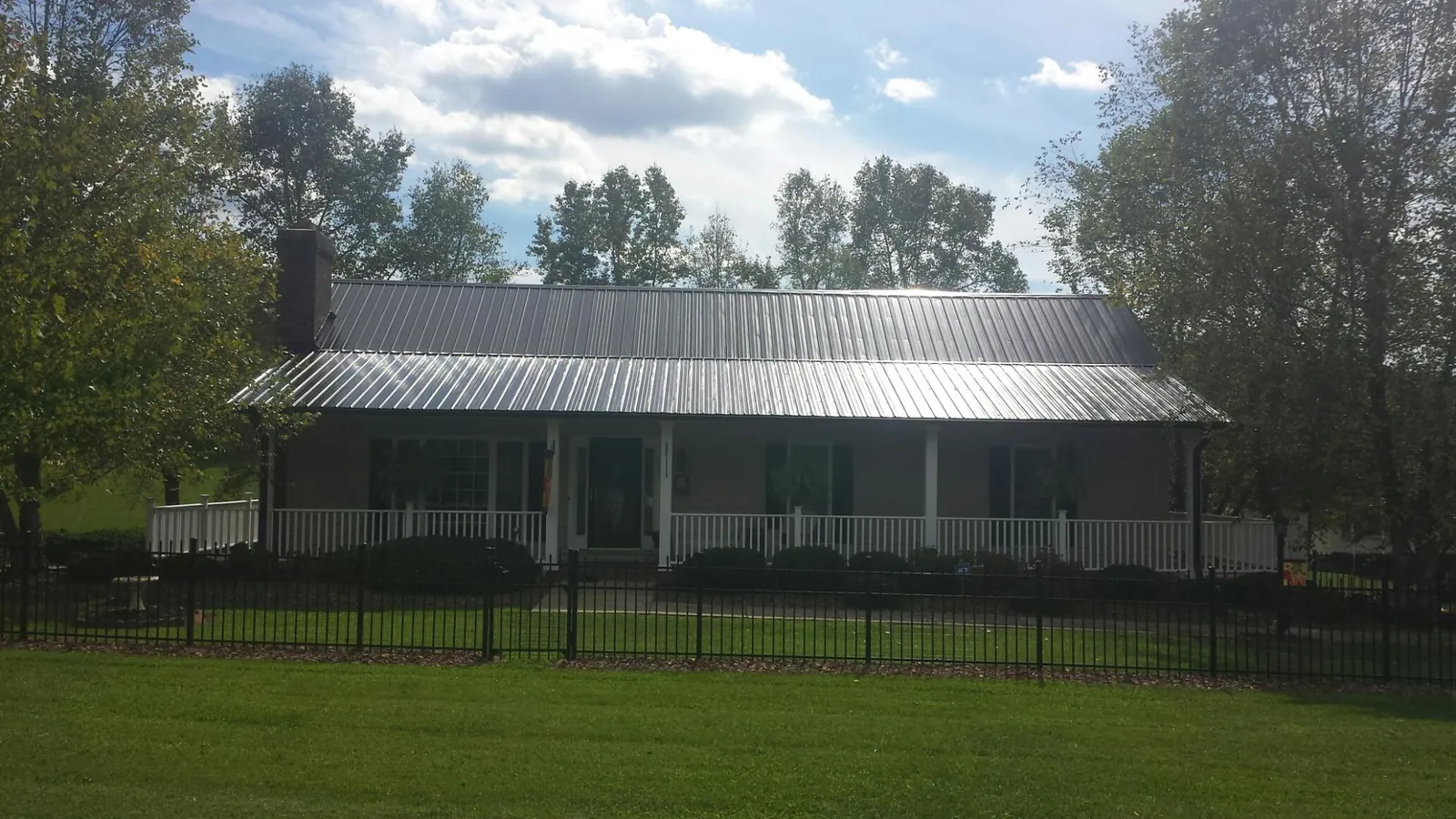 Gray metal roof on a brick ranch with a full width front porch — Gutter Guard Installation work by our crew in Neelyton